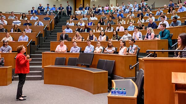 Lecture hall full of students surrounding primary teacher