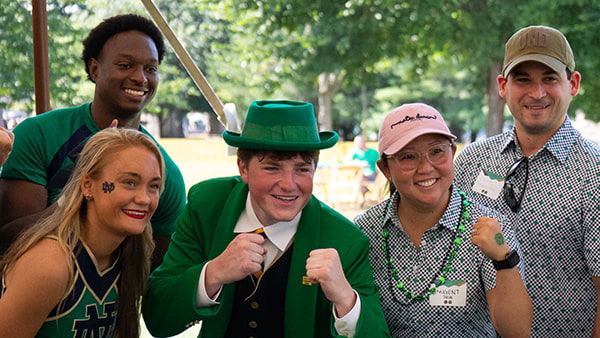 A family taking a photo with the Notre Dame Leprechaun and cheerleaders